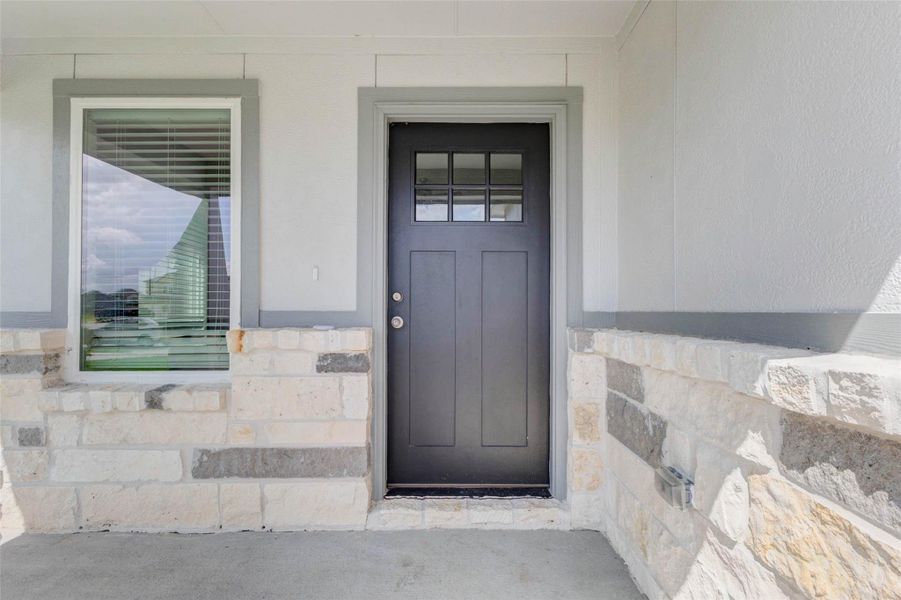 Covered front porch with stone accents, a black front door, and a front window that brings in natural light. This inviting entry gives the home a polished first impression while offering a protected space to welcome guests.