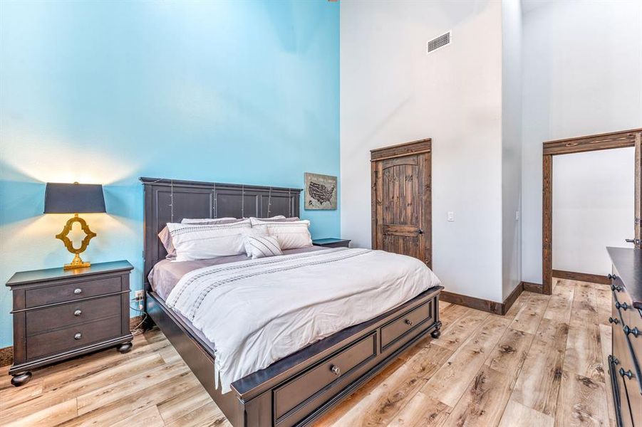 Bedroom featuring a closet, light wood-style flooring, and a towering ceiling