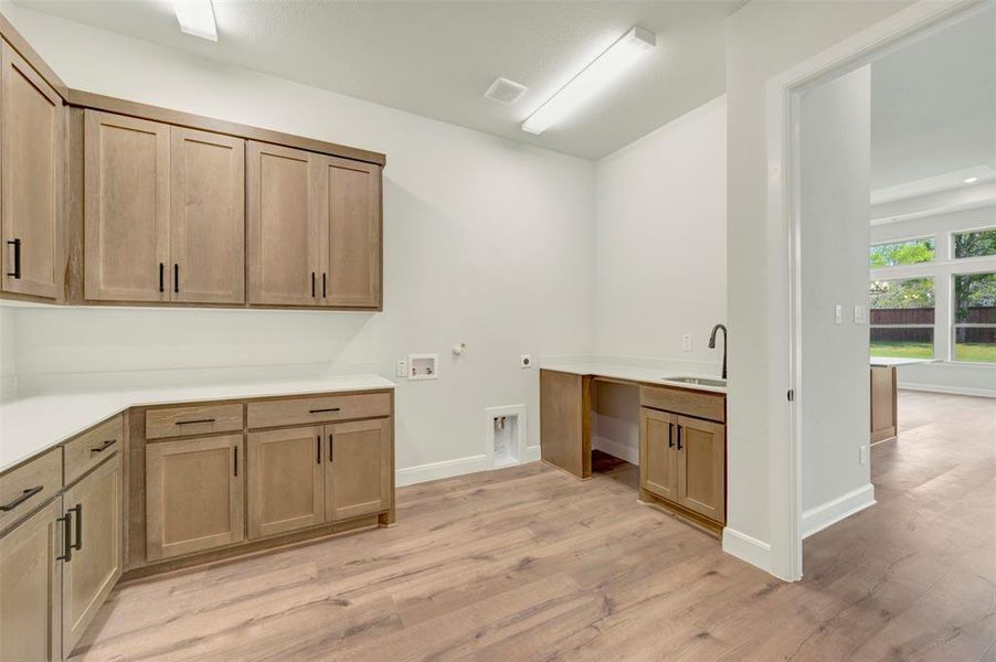 Laundry area with gas dryer hookup, light wood-style floors, washer hookup, cabinet space, and hookup for an electric dryer