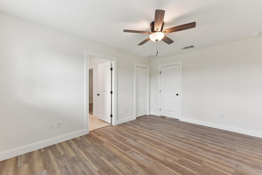 Bedroom 2 with wood style finished floors, visible vents, a ceiling fan, and baseboards