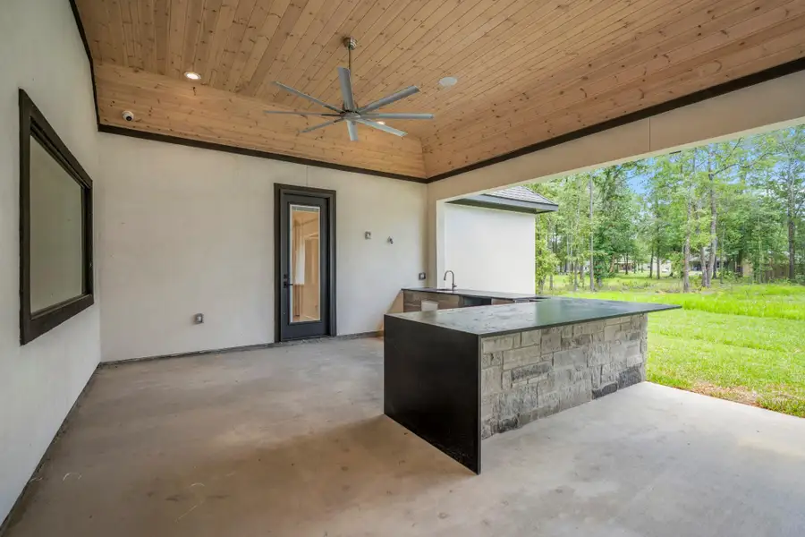 Massive end to end covered patio is anchored by this custom outdoor kitchen with beautiful stone and black granite waterfall counter top. Many outdoor parties and grilling is sure to bring families and friends together. Massive end to end covered patio is anchored by this custom outdoor kitchen with beautiful stone and black granite waterfall counter top. Many outdoor parties and grilling is sure to bring families and friends together.