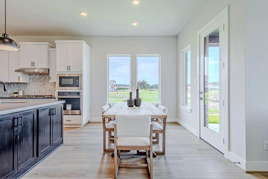 Enjoy your morning coffee with a view—this cozy dining space is bathed in natural light and framed by picture windows overlooking the greenbelt.