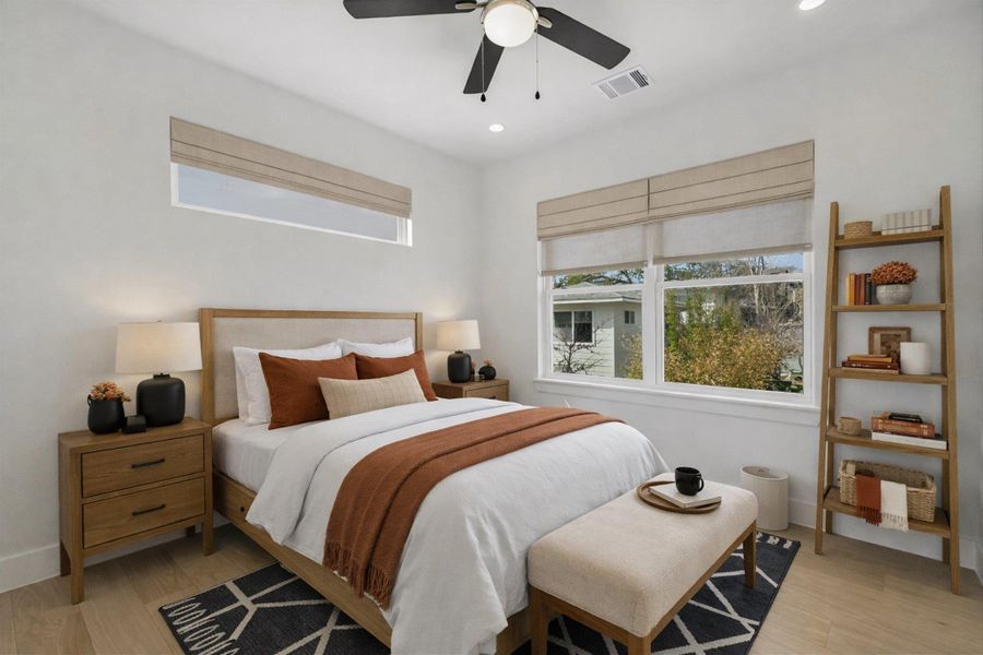 Staged photo. The secondary bedroom features tons of natural light and the beautiful floors that continue seamlessly throughout the home.