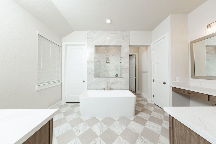 The centerpiece of this contemporary primary bath is the deep, freestanding bathtub with gorgeous marble tile offering an ideal spot for relaxation with a unique view into the walk-in shower. The flooring features large square tiles set in a timeless diagonal, checkerboard pattern, adding visual interest and depth to the space.