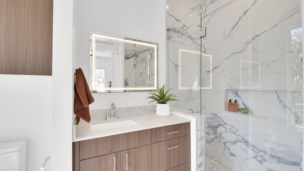 Guest suite bathroom featuring vanity and a marble finish shower