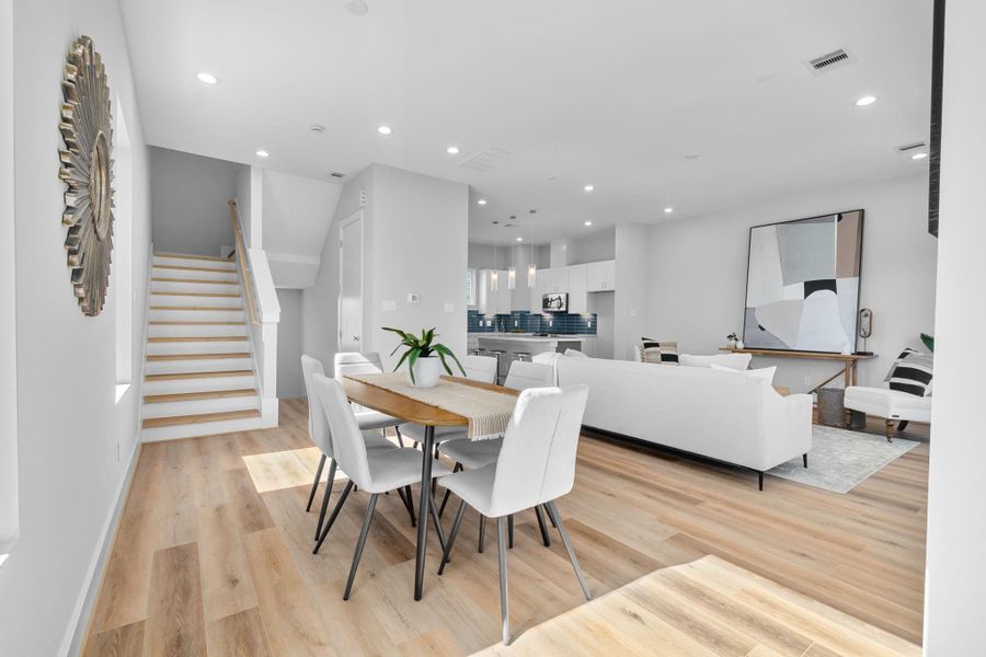 Dedicated dining space positioned alongside the living area, highlighted by large windows and a clean-lined staircase that enhances the home’s modern design.
