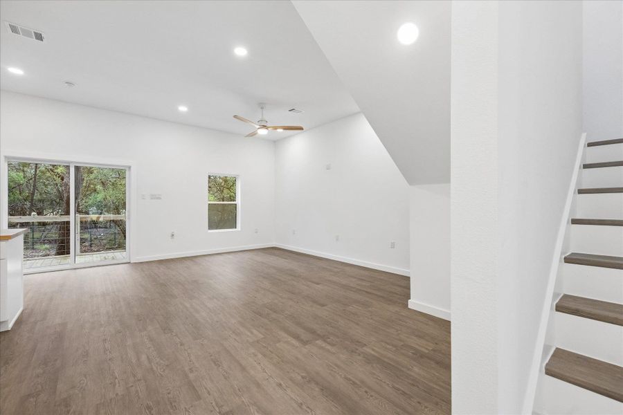 A spacious living area with tall ceilings and abundant natural light from the large glass sliding doors and window.