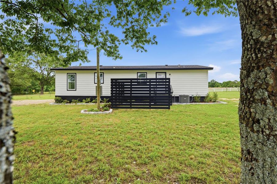 White horizontal siding with dark trim, featuring multiple windows and a black horizontal slat privacy screen