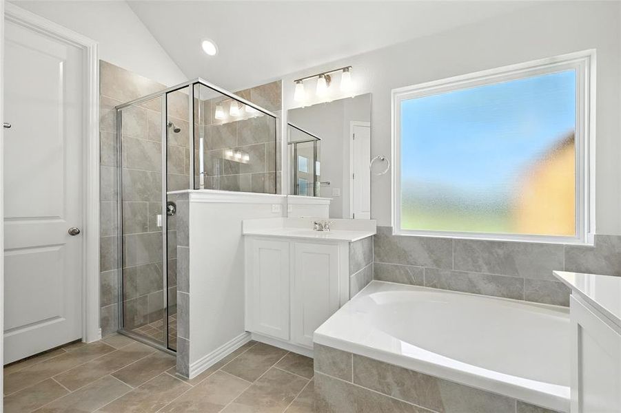 Full bathroom with vanity, a bath, a shower stall, tile patterned floors, and lofted ceiling Full bathroom with vanity, a bath, a shower stall, tile patterned floors, and lofted ceiling