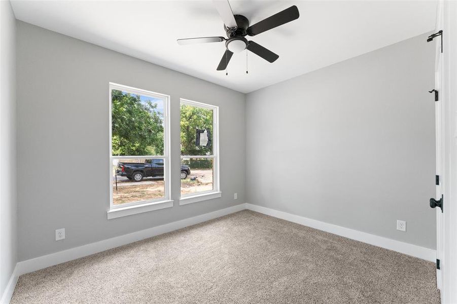 Carpeted spare room featuring baseboards and a ceiling fan