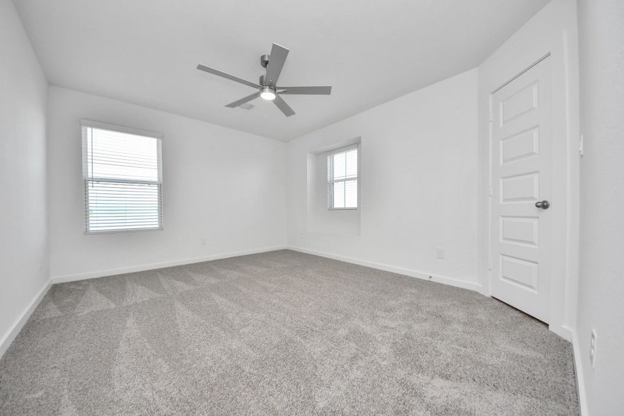 Secondary bedroom features plush carpeting, large windows that let in plenty of natural light, bright paint, and spacious closets. Sample photo of completed home with similar floor plan. Actual colors and selections may vary.