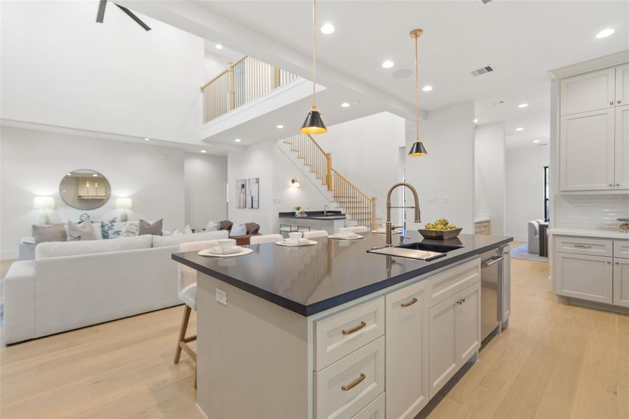 Your oversized kitchen island anchors the heart of the home, giving you the perfect spot for morning coffee, casual meals, or hosting friends while still staying connected to the living room and staircase beyond. The sleek, dark countertops contrast beautifully with soft cabinetry and warm wood floors, while statement pendant lighting adds just the right touch of drama. Whether you’re plating dinner, pouring wine, or setting up for a game night, this space effortlessly keeps everything together.