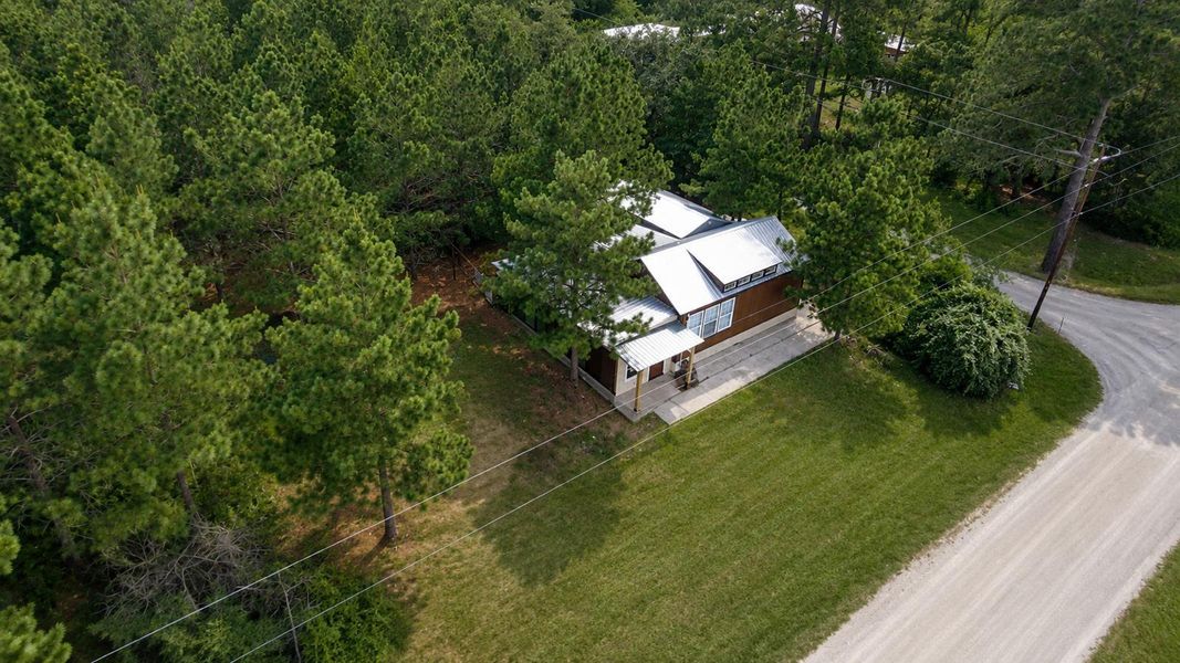 Nestled amidst verdant pines, a charming brown-sided home offers tranquil, wooded living.