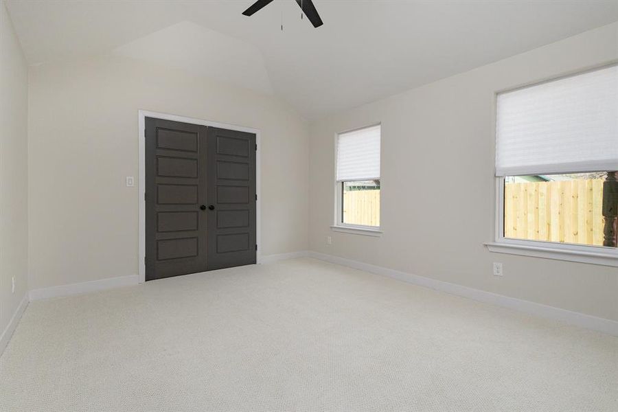 Carpeted empty room with baseboards, lofted ceiling, and ceiling fan