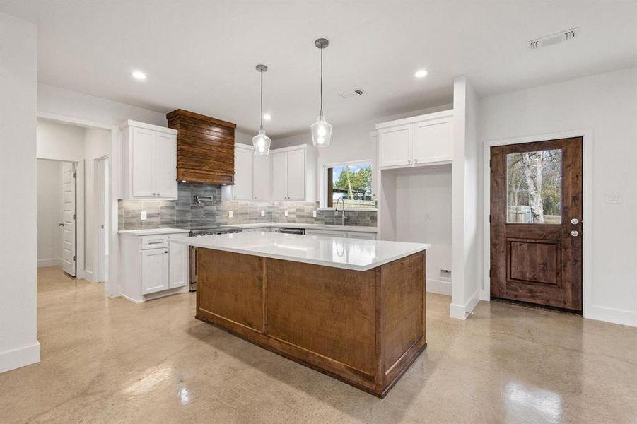 Kitchen with a kitchen island, white cabinetry, decorative light fixtures, concrete flooring, and recessed lighting