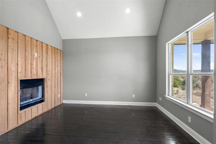Unfurnished living room with dark wood finished floors, a fireplace, recessed lighting, and high vaulted ceiling