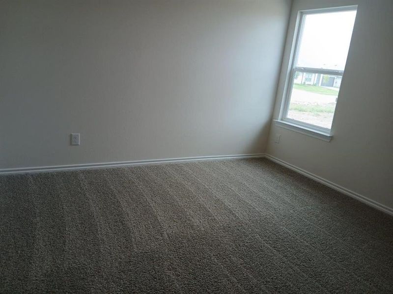 Neutral wall finish with white trim, a single window, and textured carpet flooring Neutral wall finish with white trim, a single window, and textured carpet flooring