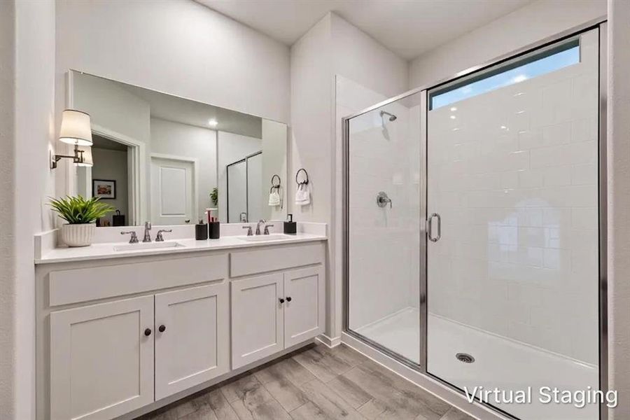Contemporary bathroom featuring a double vanity with white cabinetry and countertop, dual undermount sinks, and a frameless glass-enclosed shower with subway tile surround and transom window