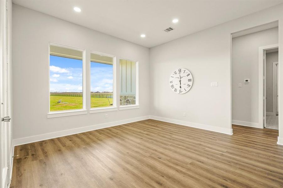 The Breakfast Room is located right off the Kitchen and boasts a trio of picture windows overlooking the covered Back Patio and never-ending countryside views. The opening to the right leads to the Primary Bedroom, Laundry Room, and Powder Room.