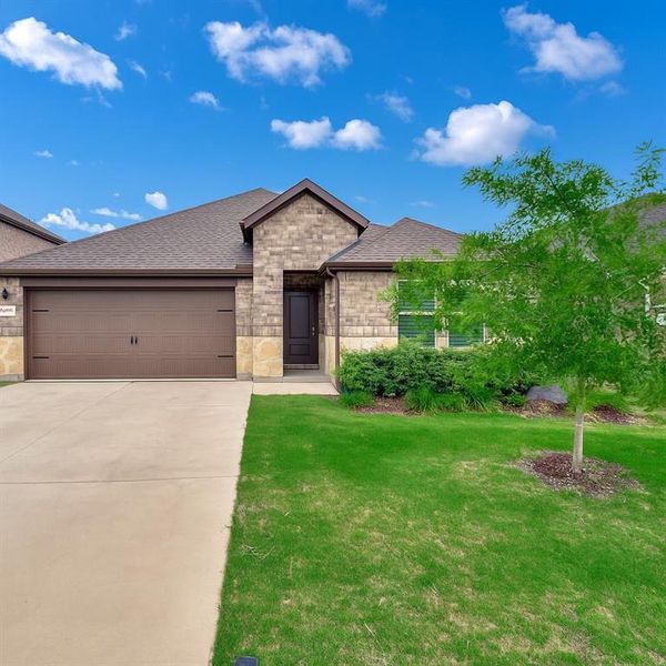 View of front facade featuring a shingled roof, a garage, a front lawn, brick siding, and concrete driveway