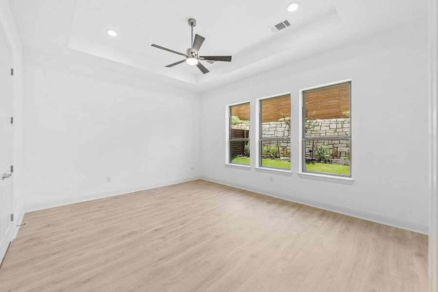 Spare room with a tray ceiling, light wood finished floors, recessed lighting, and a ceiling fan