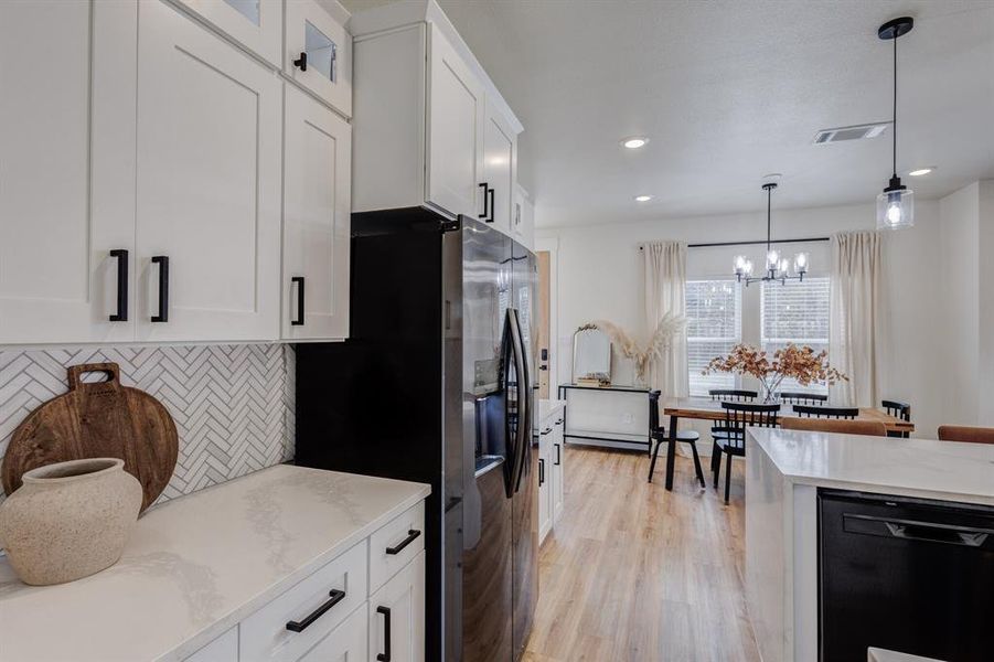 Kitchen featuring light hardwood / wood-style flooring, dishwasher, white cabinetry, backsplash, and hanging light fixtures Kitchen featuring light hardwood / wood-style flooring, dishwasher, white cabinetry, backsplash, and hanging light fixtures