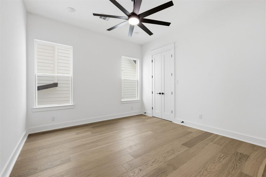 One of two secondary bedrooms located on the second floor, complete with ceiling fans, recessed lighting, and a spacious walk-in closet.
