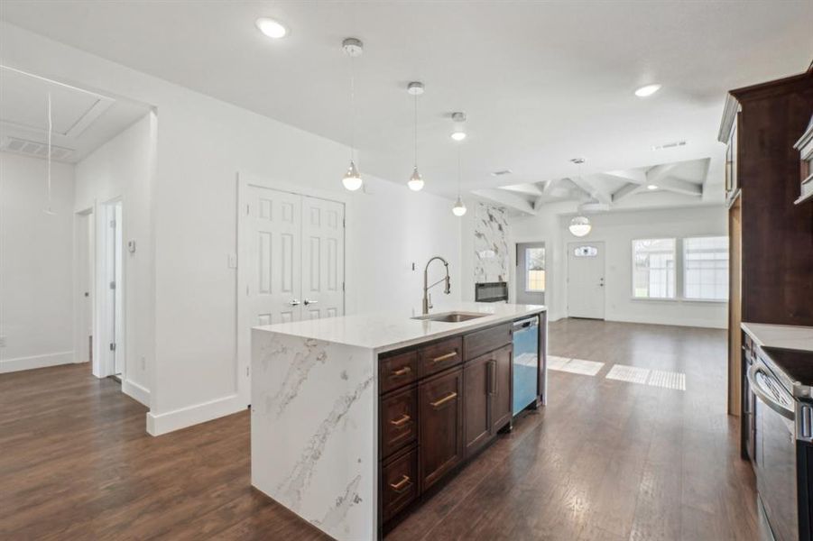 Kitchen with beam ceiling, sink, stainless steel appliances, coffered ceiling, and an island with sink