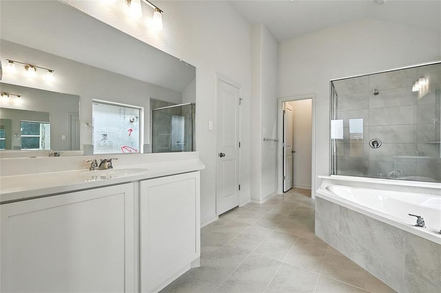 Full bath featuring a shower stall, a bath, vanity, light tile patterned floors, and lofted ceiling