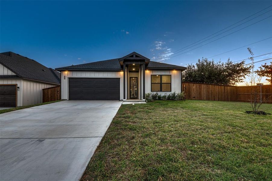 View of front of property featuring a lawn and a garage