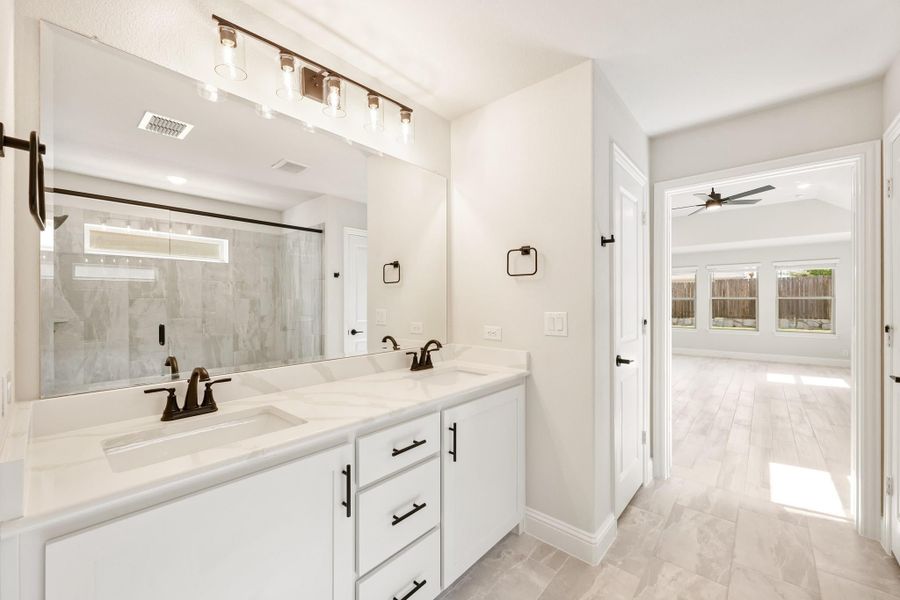 Ensuite bathroom with double vanity, white cabinets, quartz countertop, and large mirror with bar lighting Ensuite bathroom with double vanity, white cabinets, quartz countertop, and large mirror with bar lighting