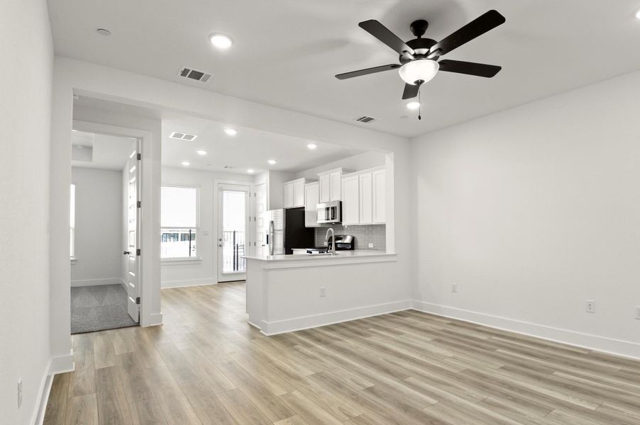 Kitchen featuring white cabinets, light wood-type flooring, a peninsula, open floor plan, and recessed lighting