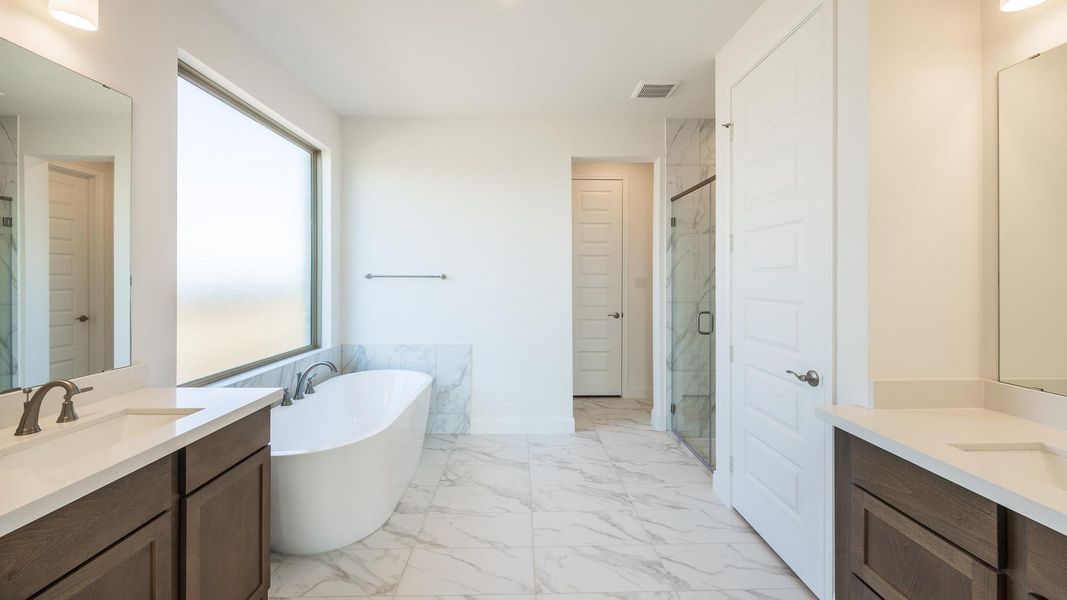 Full bathroom with a marble finish shower, a soaking tub, light marble finish flooring, and two vanities Full bathroom with a marble finish shower, a soaking tub, light marble finish flooring, and two vanities