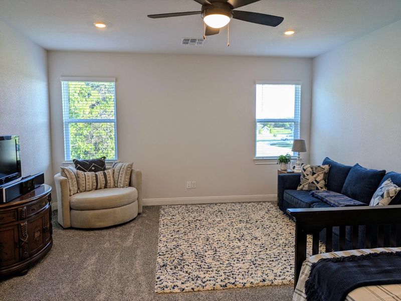 Well-lit room featuring soft carpeting and a ceiling fan for comfort.