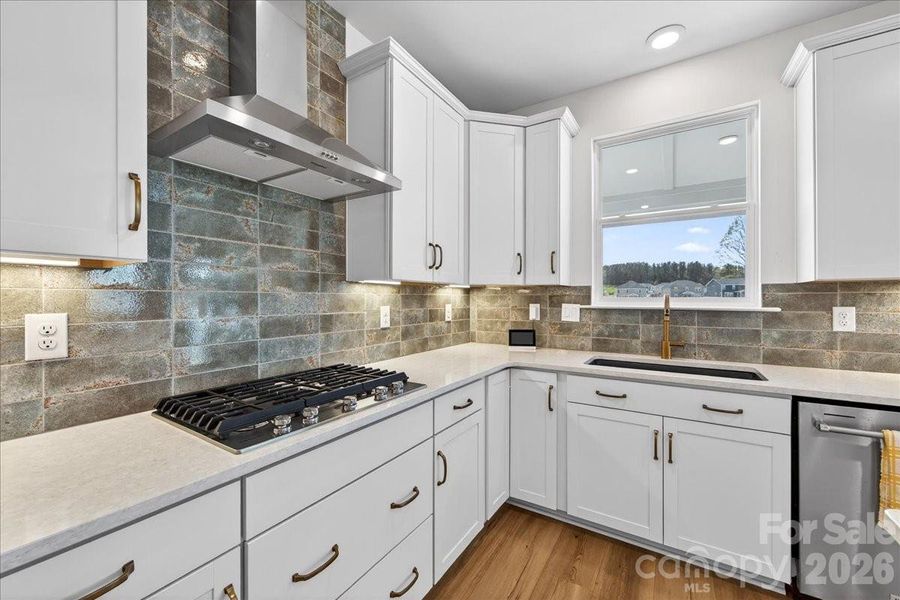 Unique tile backsplash and champagne bronze finishes elevate this chef's kitchen.