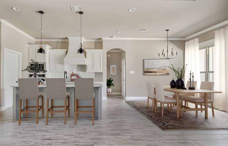 Kitchen with white cabinets, decorative light fixtures, a kitchen bar, and premium range hood