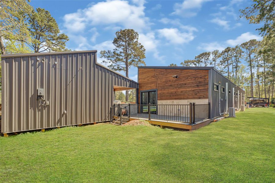 Metal and wood exterior, featuring a spacious deck and surrounded by lush greenery. Ideal for those seeking contemporary design and tranquility.