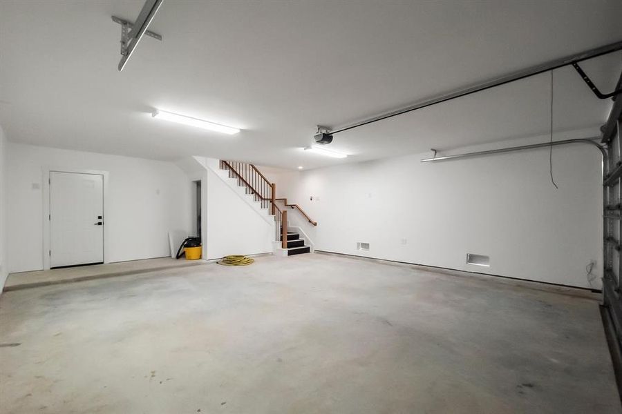 spacious garage featuring extra storage and a convenient door leading to the ground-level cemented area.