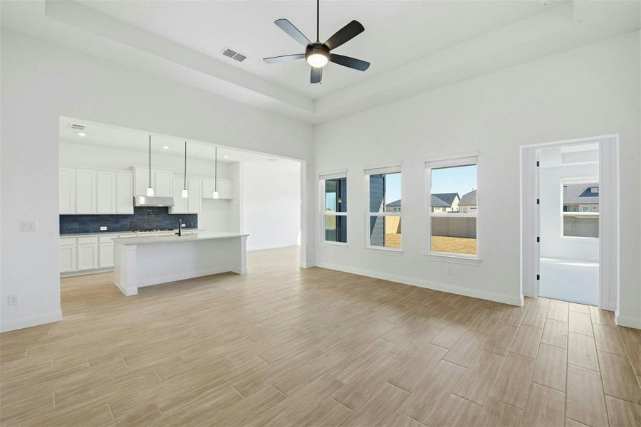 Unfurnished living room with wood tiled floors, ceiling fan, and a raised ceiling