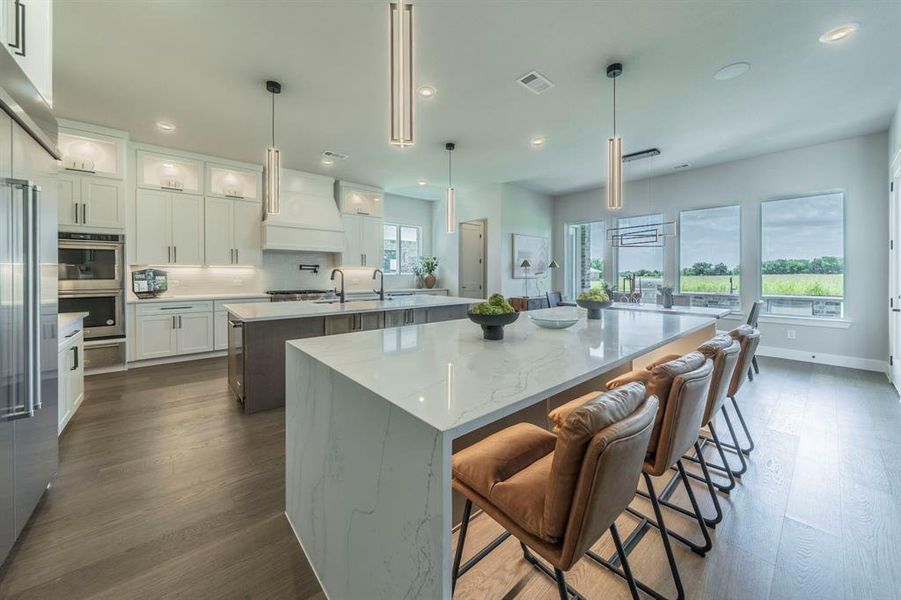 Kitchen with a large island, recessed lighting, premium range hood, white cabinetry, and glass insert cabinets Kitchen with a large island, recessed lighting, premium range hood, white cabinetry, and glass insert cabinets