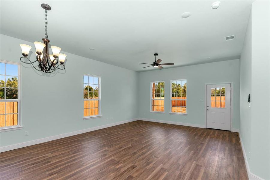 Unfurnished living room with dark wood-style flooring, ceiling fan, and a chandelier