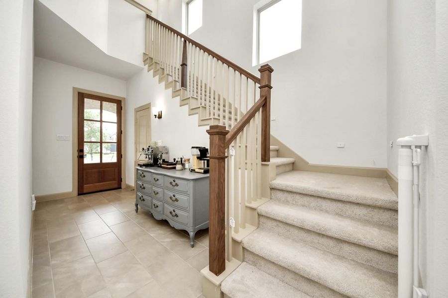 This inviting entrance features soft elegant wood railings leading upward, creating a stylish first impression.