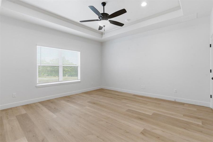 Spare room featuring a raised ceiling, light wood-style flooring, ceiling fan, ornamental molding, and recessed lighting Spare room featuring a raised ceiling, light wood-style flooring, ceiling fan, ornamental molding, and recessed lighting