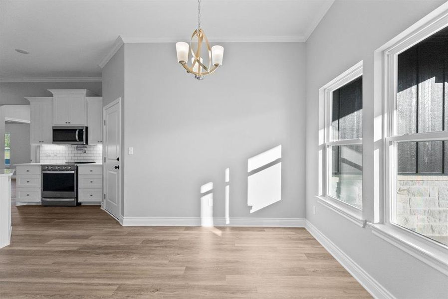 Unfurnished dining area featuring ornamental molding, a chandelier, and light wood-style floors