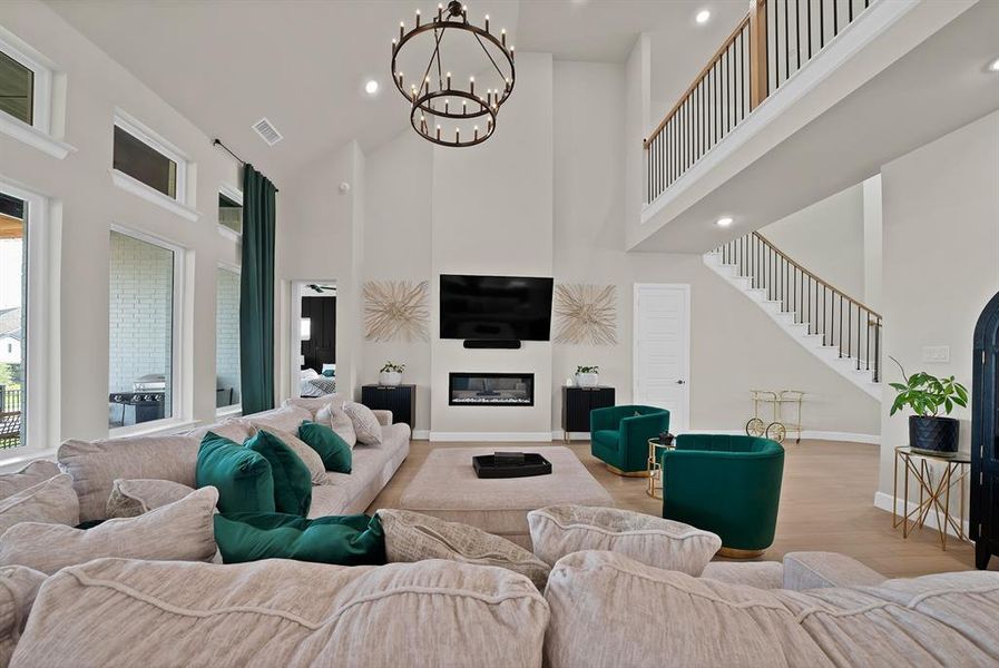 Two-story living area featuring a prominent fireplace, integrated television, and a double-tier chandelier Two-story living area featuring a prominent fireplace, integrated television, and a double-tier chandelier