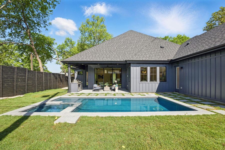 Rear view of house featuring board and batten siding, a shingled roof, a patio area, and a pool with connected hot tub