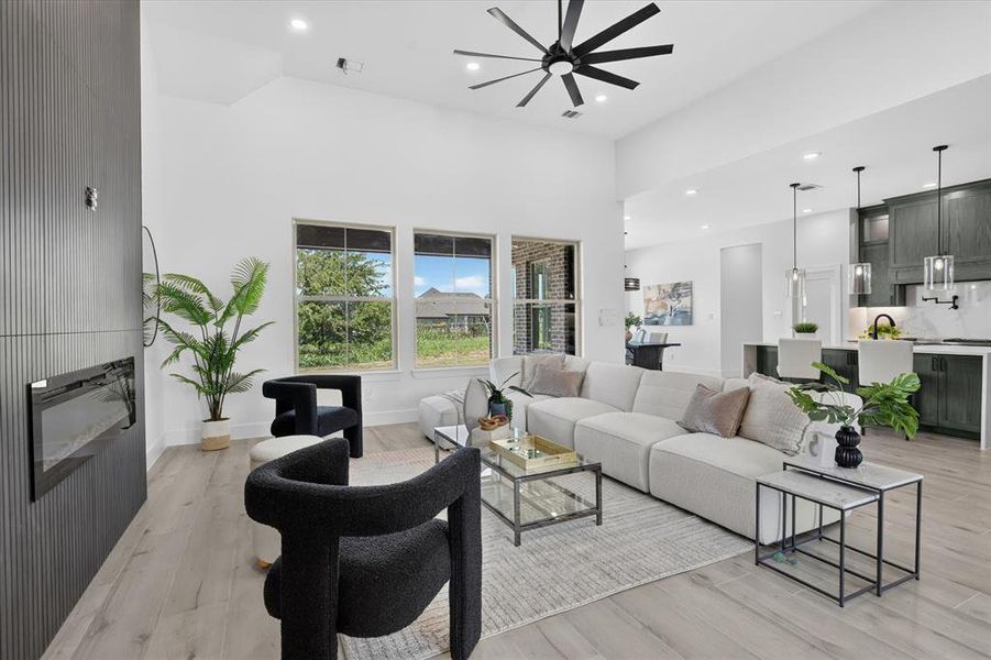 Spacious living area featuring a vaulted ceiling with a modern ceiling fan, recessed lighting, and light wood-finish flooring