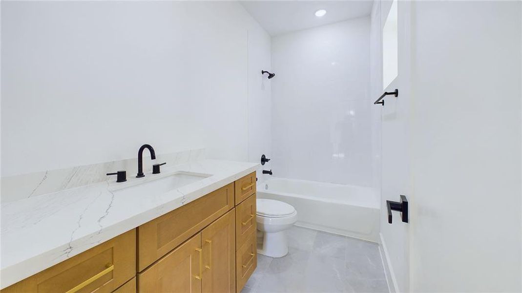 This stylish ensuite bath showcases elegant finishes throughout. A spacious vanity is lined with calacatta quartz with an under-mount sink and added storage is topped with gold hardware while the tub and shower combo is framed by classic white subway tiles, creating a clean and timeless look.