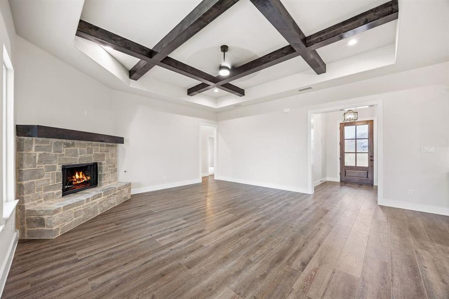 Unfurnished living room featuring coffered ceiling, a stone fireplace, wood finished floors, recessed lighting, and a ceiling fan Unfurnished living room featuring coffered ceiling, a stone fireplace, wood finished floors, recessed lighting, and a ceiling fan