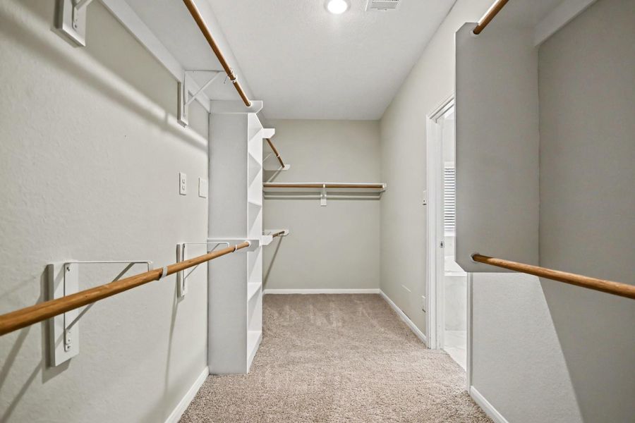 Spacious walk-in closet with ample shelving and hanging space.